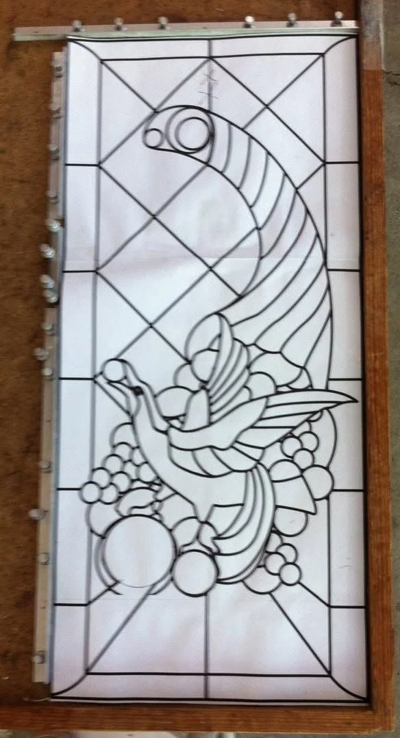 Full-size blue bird and cornucopia line pattern held in assembly guides